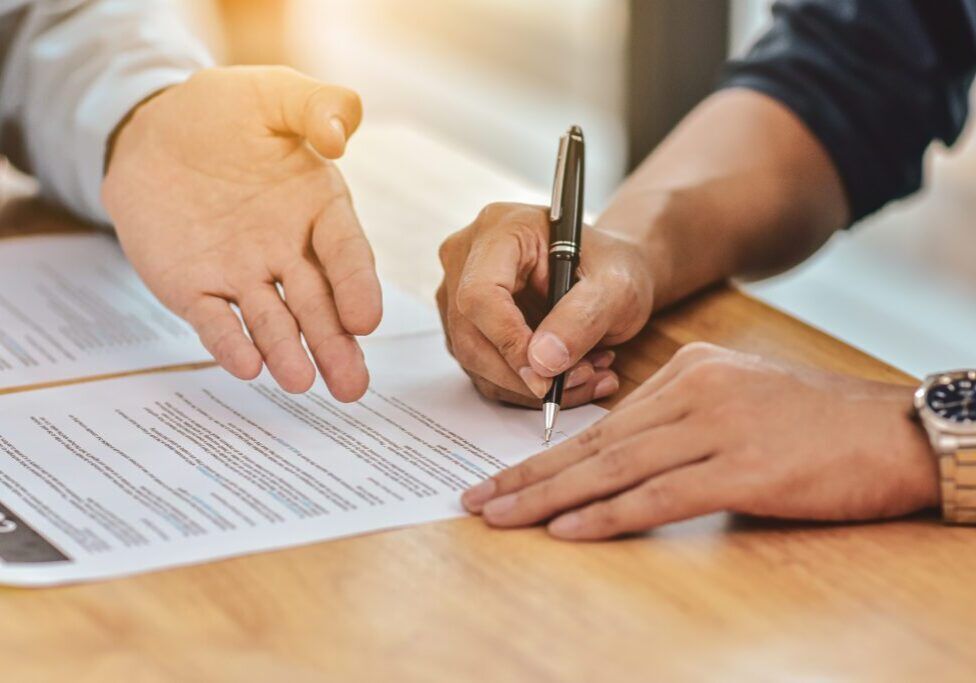 Close up hand holding pen sign contract on document